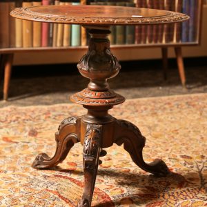 41.  Lamp table. English solid walnut with center inlay depicting a warrior on horseback. With intricate carving overall. Splayed base. Late 19th century. 