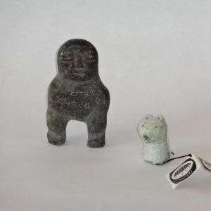145.  Two Inuit soapstone carvings.  Grey grained figure of a man, signed in syllabics, and jade-coloured Bear's Head, numbered on bottom.