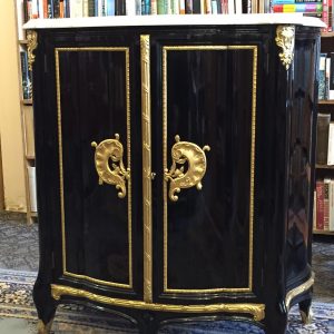 (one of two) 39. Italian commode.  Black lacquer with marble top and orate brass fittings.  Opening to multiple shelves.  Mid 20th century.